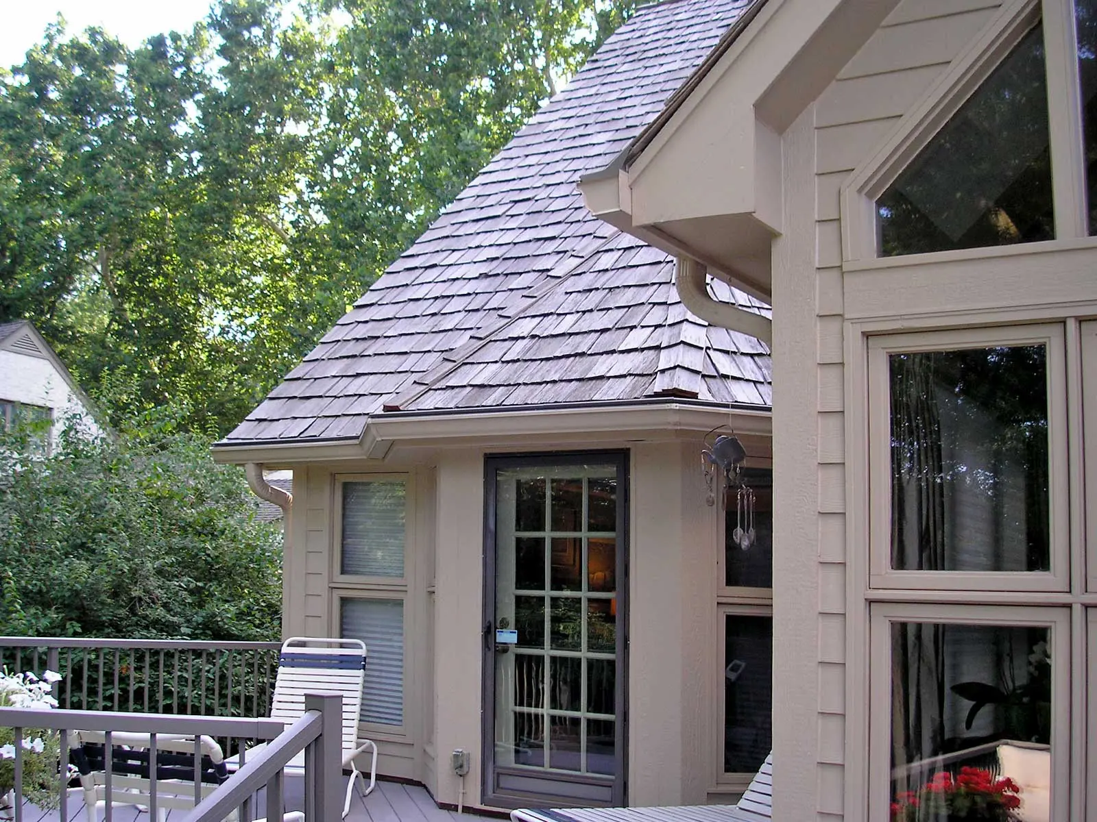 A mature tree canopy over an Omaha-area home: the seasonal leaf and seed drop that fills an open gutter.